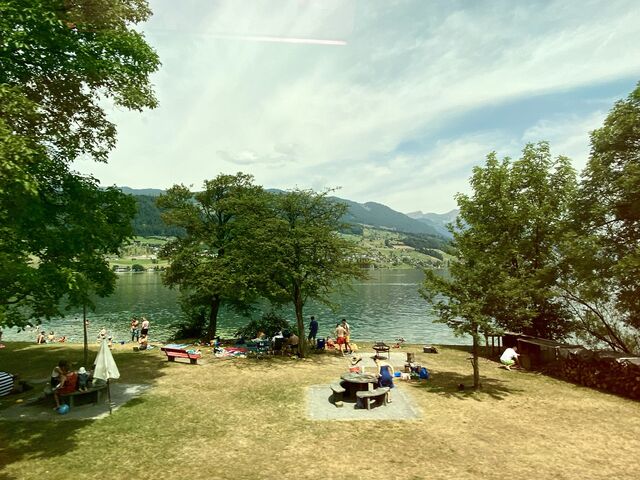 People swimming and picnicking on the banks of Lake Sarnen near the village of Sachseln